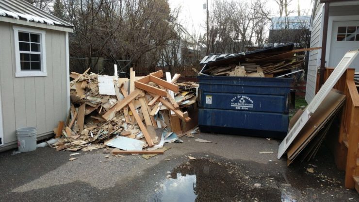 A pile of debris larger than the full dumpster sitting next to it.