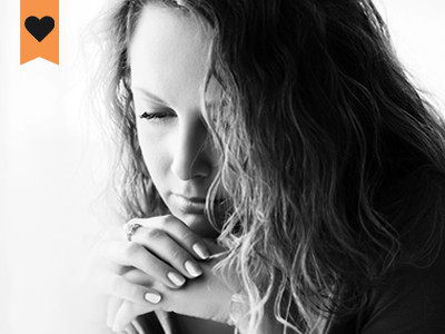 woman resting her head on her hands looking down in deep thought