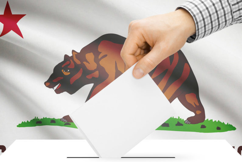 ballot being inserted into box with California flag in background