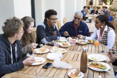 students and family members gathered for lunch at outdoor table