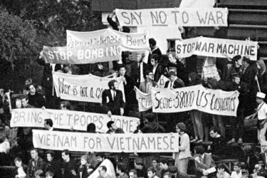 Students holding protest signs at a football game
