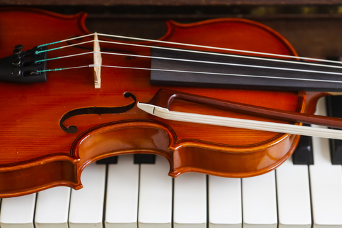 Photo of a violin and bow on piano keys