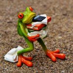 toy frog holding a falling stack of papers