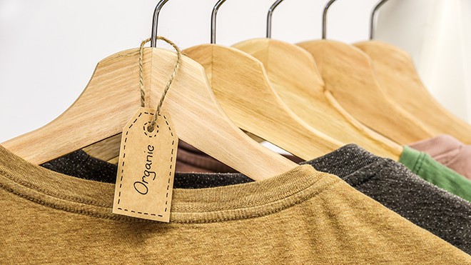 How-To-Shop-For-Ethical-Fashion-On-A-Budget-clothes-hanging-on-a-rack-with-the-tag-organic