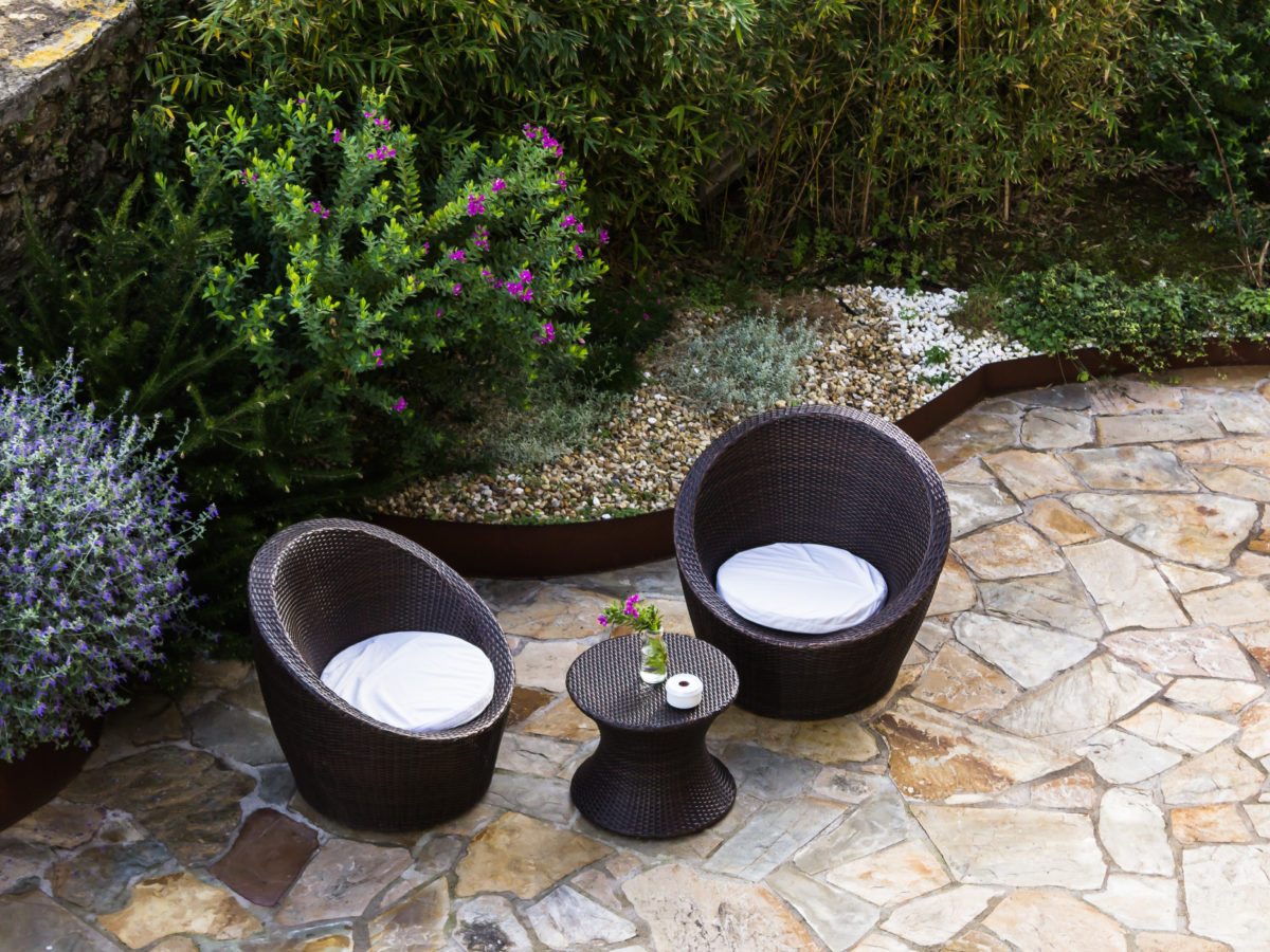 Flagstone patio in backyard with furniture and crushed rock