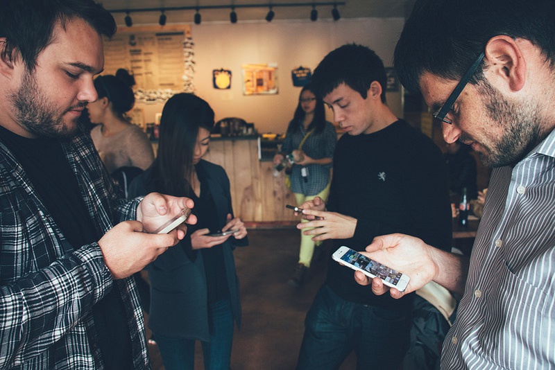A group of people all looking at their phones A group of people all looking at their phones