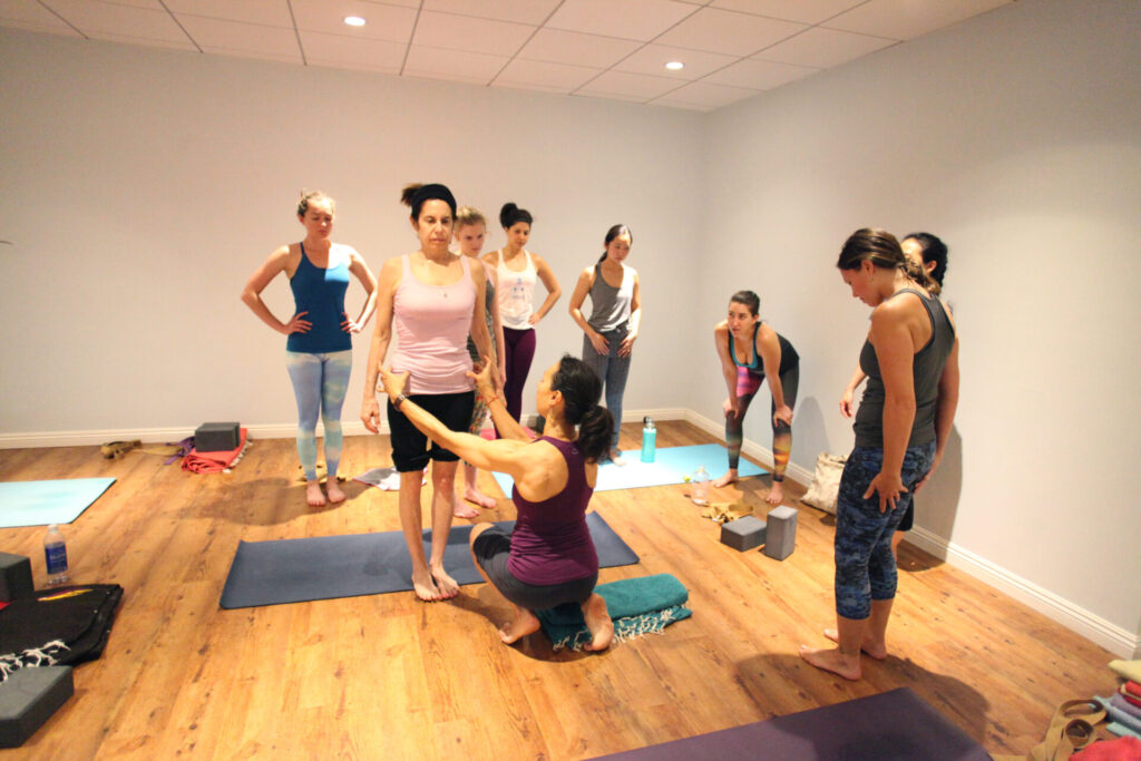 Aria Morgan assisting student in finding neutral hips at Yoga Raj during Aria's signature Turn Your Fear Upside Down workshop